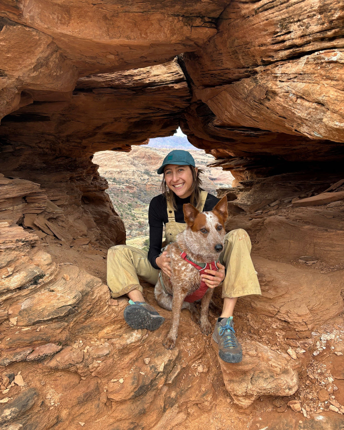 Madison Brandt sitting with her dog in a sandstone arch